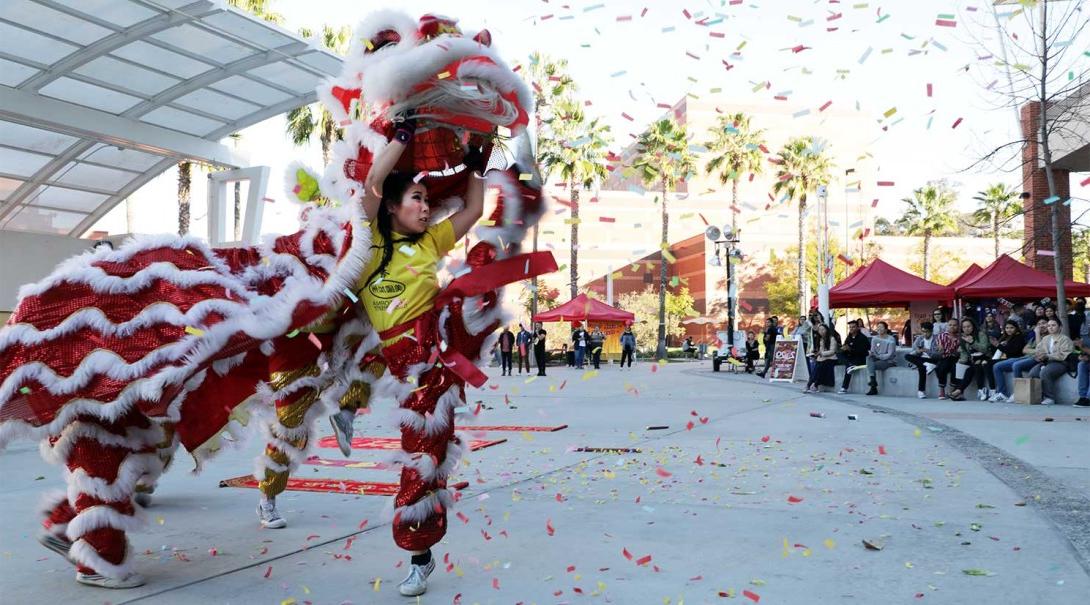 An Asian female student dancing in a lion costume